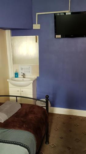 a bedroom with a blue wall with a bed and a sink at Hour Glass Hotel in London