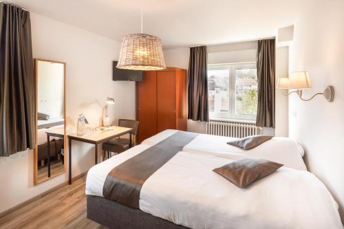 ein Hotelzimmer mit einem großen Bett und einem Schreibtisch in der Unterkunft Parkhotel in De Panne