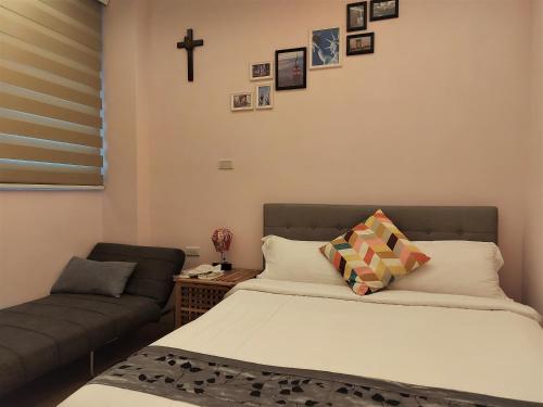 a bedroom with a bed and a couch and a cross on the wall at Dosun B&B in Jiufen
