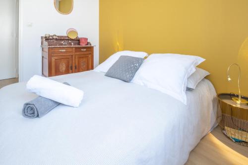 uma cama branca com almofadas brancas e uma mesa de madeira em Le Coton em Saint Malo