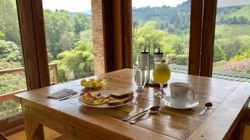 a wooden table with a plate of food and a glass of orange juice at Rancho San Antonio in Salento