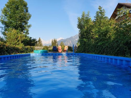 a swimming pool with blue water and trees at Pension Lindbichler in Vorderstoder