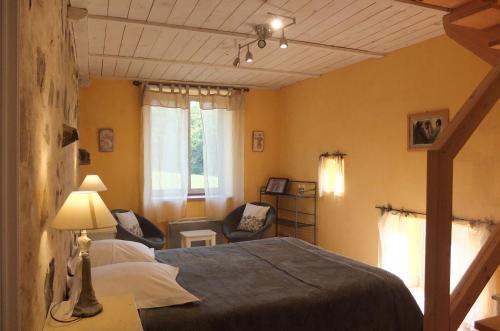 a bedroom with a bed and two chairs in it at La Pierre Folle Chambres d'Hôtes in Cluny