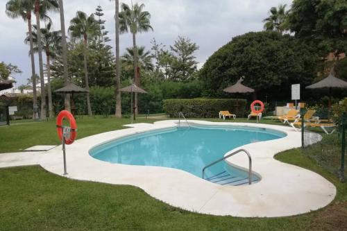 een zwembad in een tuin met palmbomen bij Las Brisas Bahia Marbella in Marbella