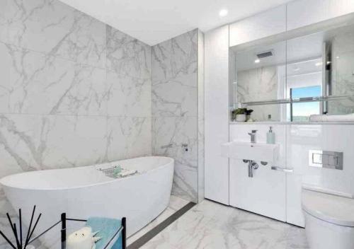 Baño blanco con bañera y lavamanos en Stylish Penthouse with Views & Jacuzzi, en Gosford