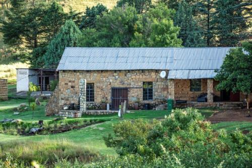 a stone house with a metal roof on a field at Old Mill Drift Guest Farm in Clarens