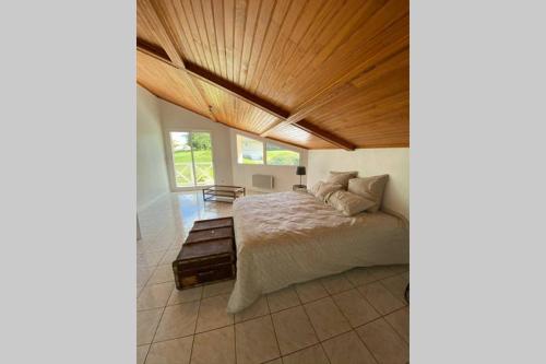een slaapkamer met een bed en een houten plafond bij Villa Alba. Piscine grand jardin Hauts de Bordeaux in Carignan