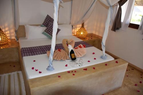 a bedroom with a bed with a bottle of wine at Villa Huruma in Paje