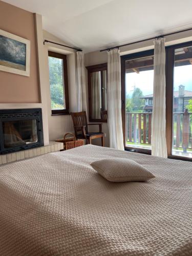 a bedroom with a bed with a fireplace and windows at Ski & Spa Chalet Bansko in Bansko