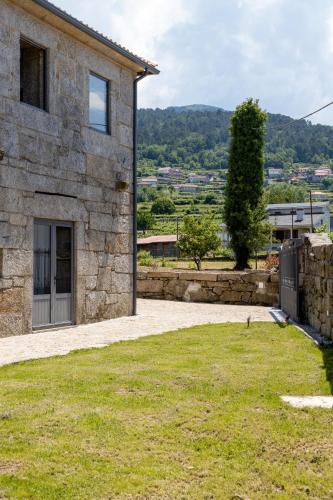 a stone house with a grassy yard next to a building at Casa da Veiga in Aldeia