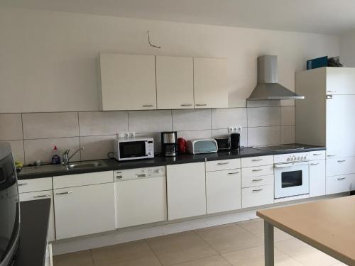 a white kitchen with white cabinets and appliances at Monteurwohnung 2 in Ingelheim am Rhein