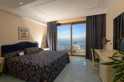 een slaapkamer met een bed en uitzicht op de oceaan bij Le Querce Resort Sea Thermae & Spa in Ischia