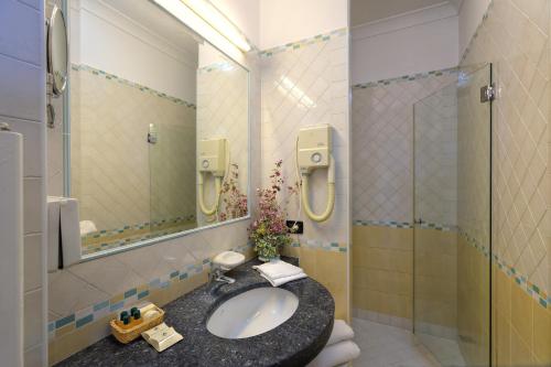 a bathroom with a sink and a shower with a mirror at Le Querce Resort Sea Thermae & Spa in Ischia