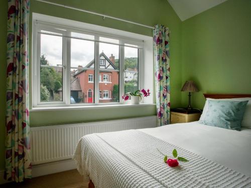 a bedroom with a bed with a white bedspread and a window at Magnolia Cottage in Church Stretton