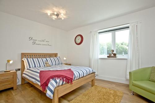 a bedroom with a bed and a clock on the wall at 19 At The Beach, Torcross in Beesands