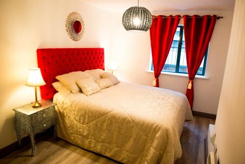 a bedroom with a red headboard and red curtains at Dublin Exchange Suites in Dublin