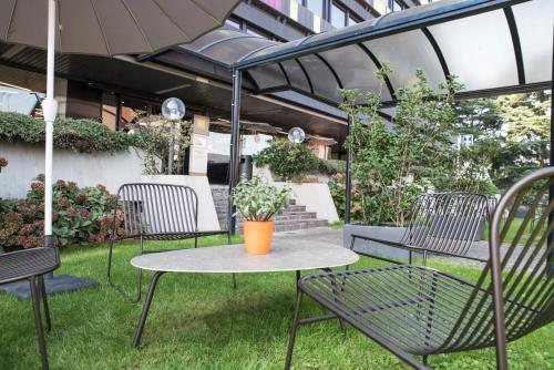 a patio with a table and chairs and an umbrella at Mercure Milano Agrate Brianza in Agrate Brianza