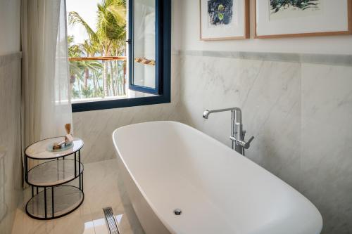 a bathroom with a white tub and a window at Hotel Fariones in Puerto del Carmen