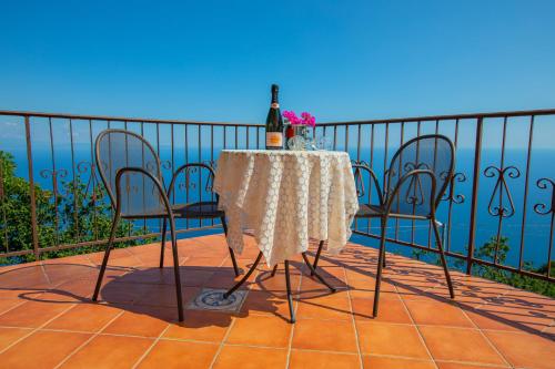 a table with two chairs and a bottle of wine on a balcony at Nido Degli Dei in Agerola