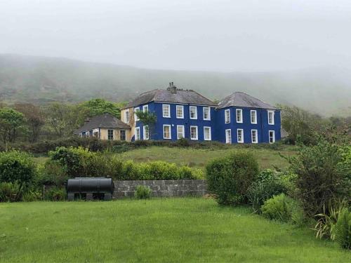 a large blue house on top of a hill at Granville House Apartments and Garden Suites in Ballyferriter