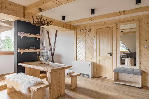Zimmer mit einem Holztisch, einer Bank und einer Tür in der Unterkunft Apartamenty w Chmurach in Kościelisko