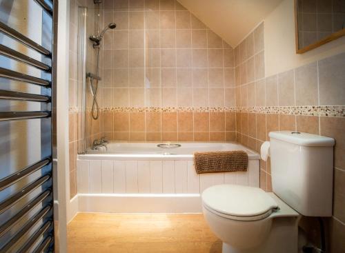 un baño con inodoro y bañera en Berries Coach House, en Church Stretton