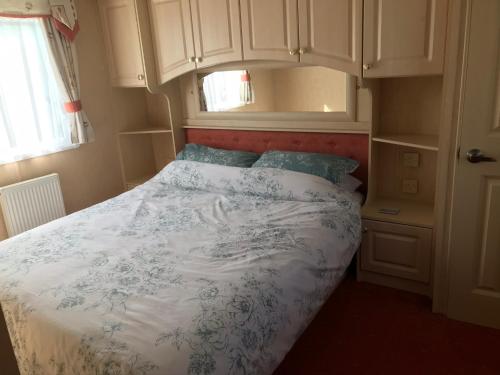 a bedroom with a bed with a blue and white comforter at Happy Days Holidays in Flamborough