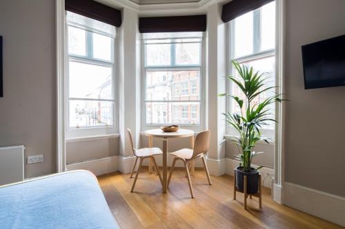 a room with a table and chairs and windows at Hausd Flex - Covent Garden in London