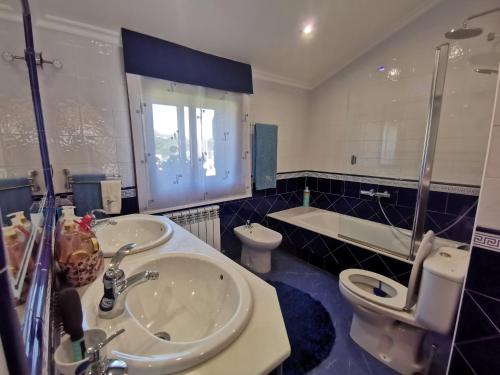 Un baño con dos lavabos, un inodoro y una bañera. en O Lar de Sara, en Pontevedra