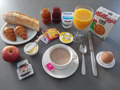 - une table avec une tasse de café et une assiette de petit-déjeuner dans l'établissement Chambre d'hôtes du Muguet avec SdB privative, au Mans