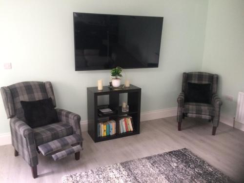 a living room with two chairs and a flat screen tv at 1 Slieve Gullion View Killeavy Newry in Newry