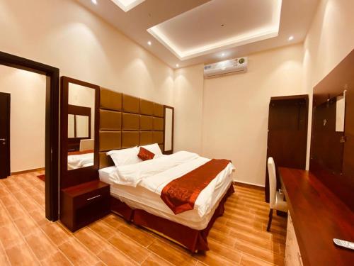 - une chambre avec un grand lit et un miroir dans l'établissement Al Hayat Al Marina Suites, à Tabuk