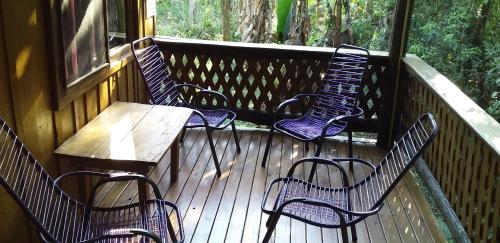 four chairs and a table on a wooden deck at Yasí Yateré Reserva Agroecológica in El Soberbio