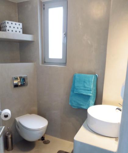 a bathroom with a toilet and a sink and a window at Plaka Sunset Naxos Home in Naxos Chora