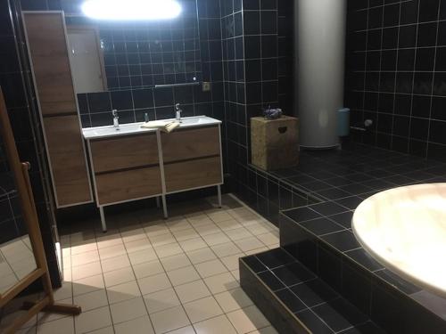 Baño de azulejos negros con lavabo y espejo en Le XIII, en Hoenheim