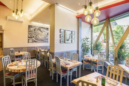 a restaurant with tables and chairs and windows at Hôtel Saint-Hubert in Saint-Claude