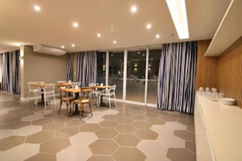 uma sala de jantar com mesas, cadeiras e janelas em Flat Edifício Royale 305 em Cabo Frio