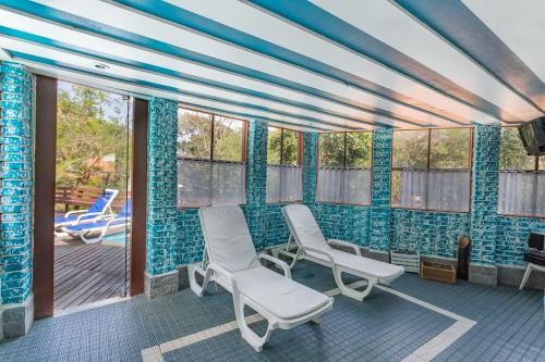 a room with two chairs on a porch with blue tiles at Wood House in Itaipava