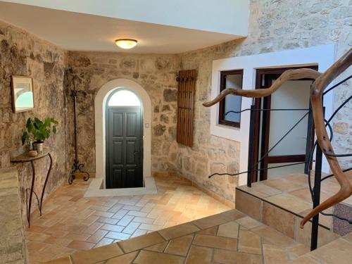 a hallway with stone walls and a black door at Casa Istriana Vrsar in Vrsar
