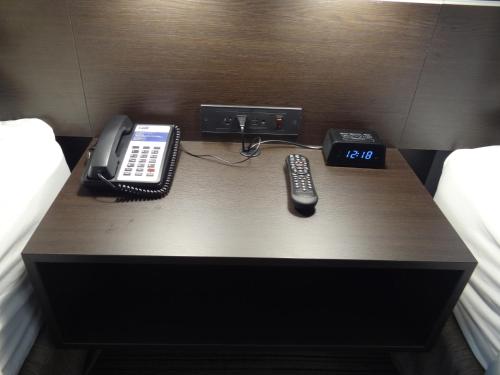 a desk with a phone and remote controls on it at Holiday Inn Express & Suites - Auburn Downtown by IHG in Auburn