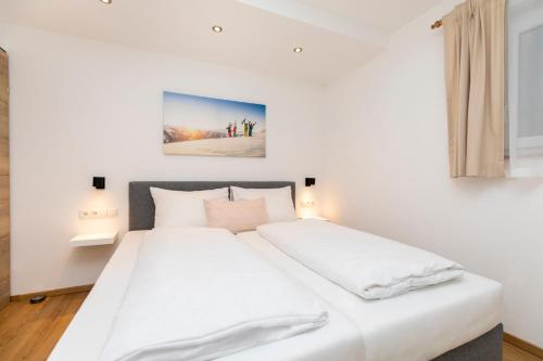 a white bedroom with a large bed with white sheets at Souterrain Apartment Flachau in Flachau