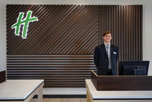 a man standing at a podium in front of a wall at Holiday Inn Grand Rapids North - Walker by IHG in Walker