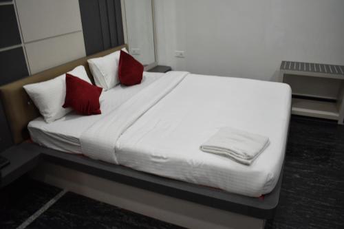 a white bed with two red pillows on it at Hotel La Vista Inn in Tinsukia