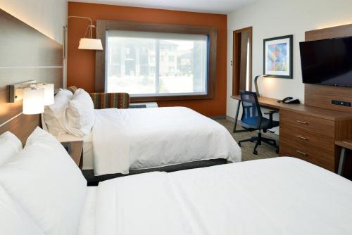 a hotel room with two beds and a desk at Holiday Inn Express & Suites - Elko by IHG in Elko