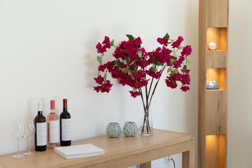 a vase with red flowers on a table with wine bottles at Ionian Trilogy Luxury Villas in Sami