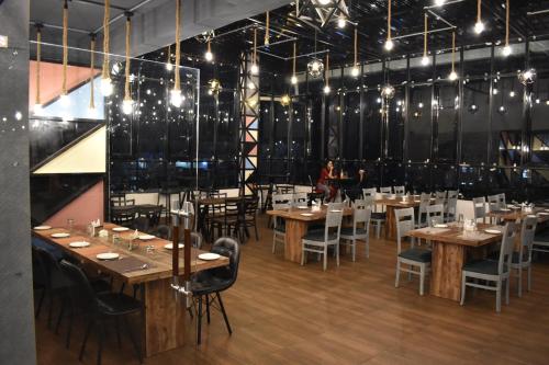 a dining room with wooden tables and chairs and a woman at Hotel La Vista Inn in Tinsukia