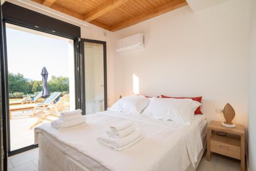 a bedroom with a white bed with towels on it at Ionian Trilogy Luxury Villas in Sami