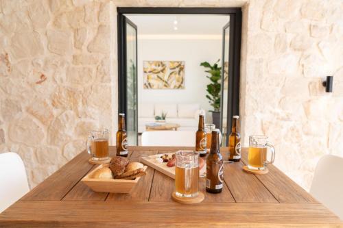 a wooden table with bread and glasses of beer at Ionian Trilogy Luxury Villas in Sami
