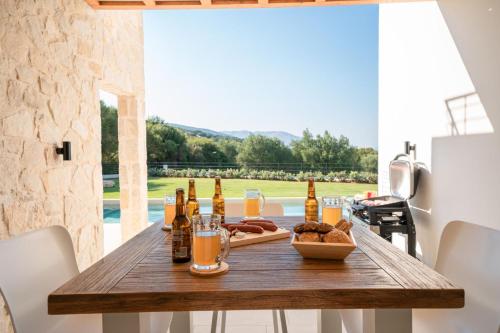 a wooden table with bottles of beer and bread at Ionian Trilogy Luxury Villas in Sami