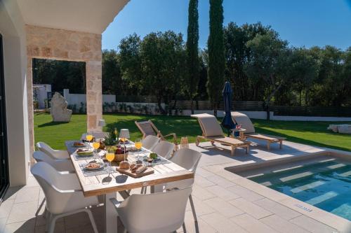 a patio with a table and chairs next to a swimming pool at Ionian Trilogy Luxury Villas in Sami